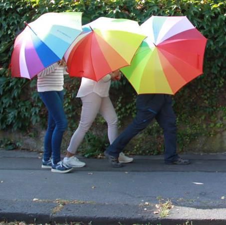 Drei Personen mit Regenschirmen, die hintereinander laufen